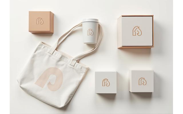Collection of branded merchandise and product packaging, including coffee mugs, tote bags, and boxes with a consistent brand identity.